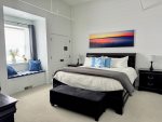 Spacious king suite with cozy layers and a sunny window seat.
